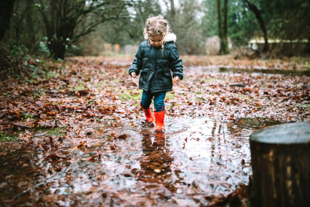 istock Little Girl Plays in Puddles From Heavy Rainfall 1296368081