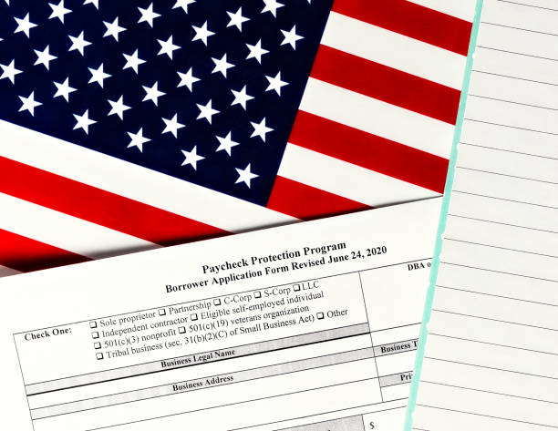 istock close-up of paycheck protection program borrower application form revised topview, on a background of United States flag. paycheck protection program new round. 1296368181