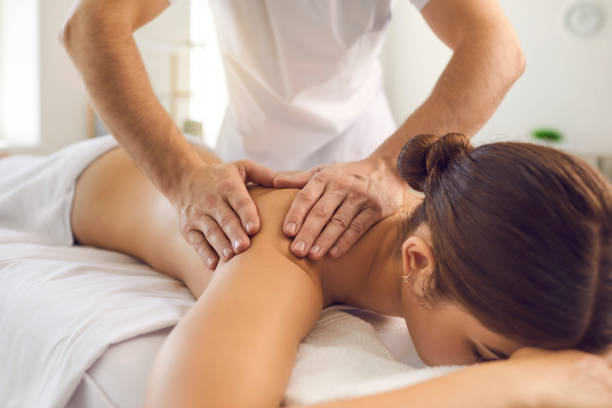 Hands of professional chiropractor or masseur making massage of back and shoulders for woman Masseur during work with patient concept. Hands of professional chiropractor or masseur making massage of back and shoulders for woman in in medical uniform in massage parlor instruction manual photos stock pictures, royalty-free photos & images