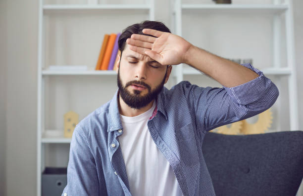 istock Young bearded man with closed eyes have headache touching forehead with back of his palm. Front view 1296368910
