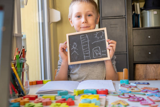 istock Little Boy Showing his blackboard with a chalk drawing 1296369071