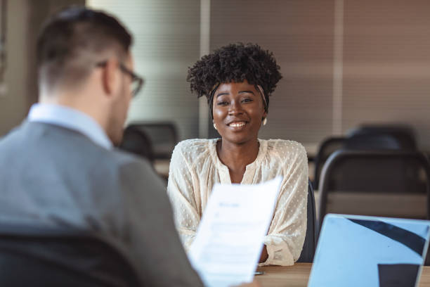 Job applicants having interview. Portrait of joyful  woman smiling and holding resume while sitting in front of businessman during corporate meeting or job interview - business, career and placement concept job interview stock pictures, royalty-free photos & images