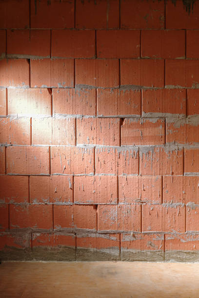 istock Rough brick wall from Porotherm style clay blocks in a construction site laterally lit, architecture background with copy space, vertical 1296373257