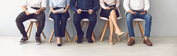istock Group of unrecognizable candidates sitting on chairs waiting for an interview. 1296378191