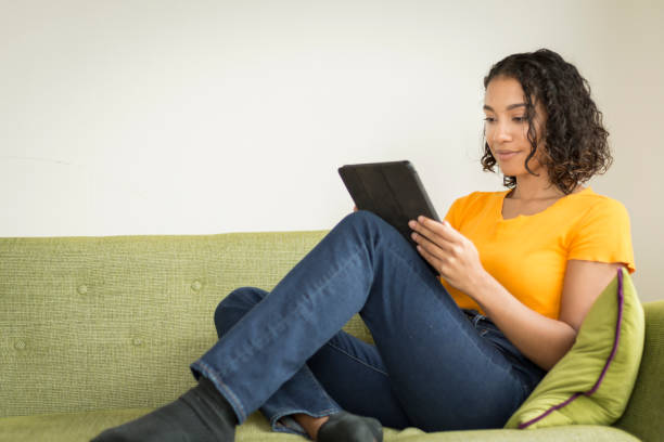 istock Happy young woman at home on sofa using a digital tablet 1296381610
