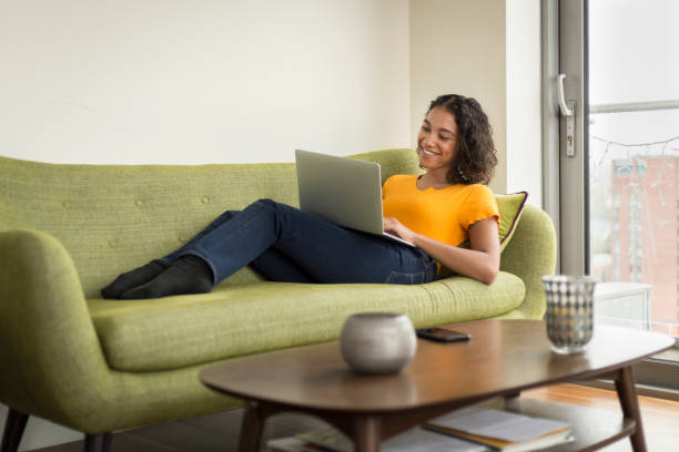 istock Happy young woman at home on sofa using a laptop 1296381699