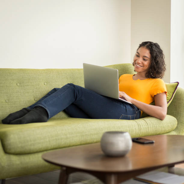 istock Happy young woman at home on sofa using a laptop 1296381706