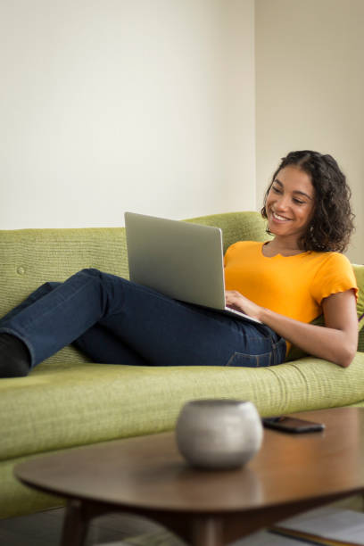 istock Happy young woman at home on sofa using a laptop 1296381718