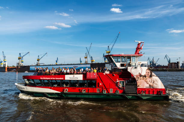 Hamburg, Germany - August 22, 2019: Cruise ship sailing with people on board and cranes in the port on the Elbe river in Hamburg, Germany