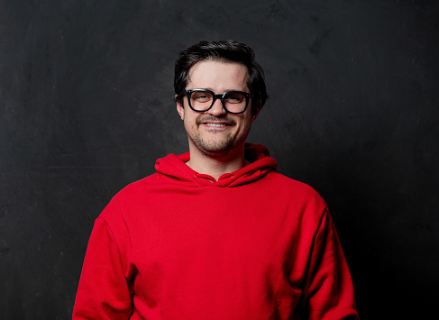 White nerd guy in red sweatshirt on dark background