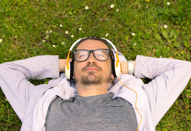 istock Above view of relaxed man with headphones lying down on grass. 1296382684