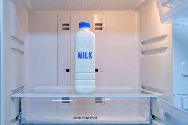 A bottle of milk stands alone in an empty refrigerator