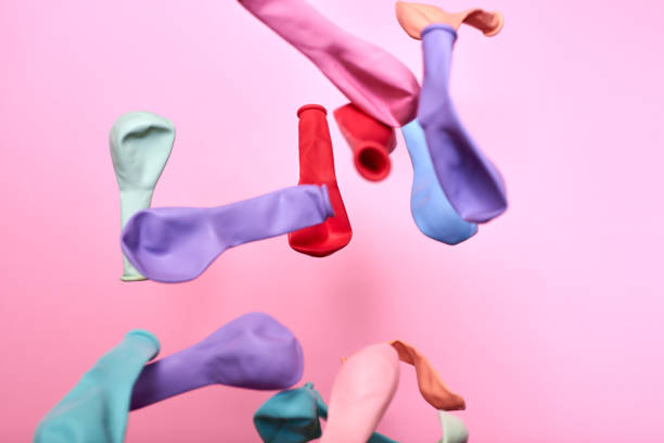 istock Multicolored not inflated balloons thrown into the air on a pink background. 1296384908