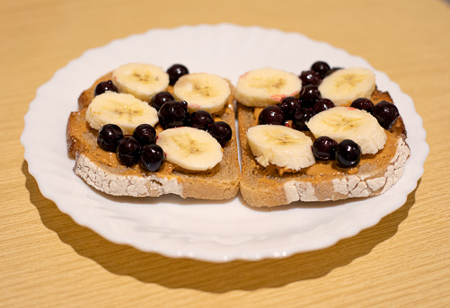 A healthy dessert for breakfast, lunch or dinner dark bread with peanut butter, black currant and banana slices