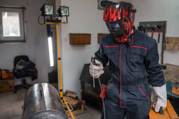 istock Welder with protective equipment in small metal workshop 1296386215
