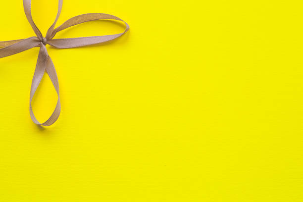 istock Yellow bright background with a gray ribbon bow in the upper left corner. Holiday concept 1296387577