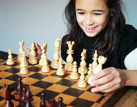 Smiling little girl playing chess