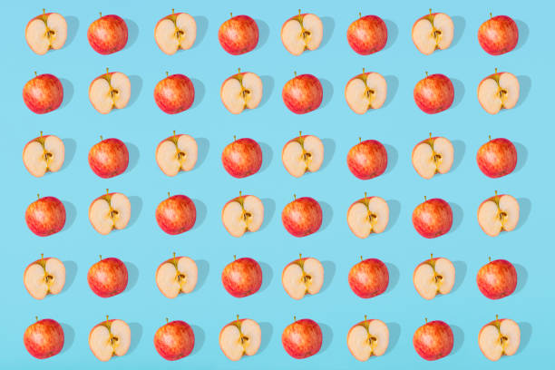 istock Outstanding pattern of fresh apple and apple halves on blue pastel background 1296392501