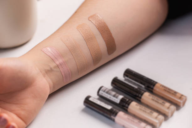 Woman testing different shades of liquid foundation on her hand and tubes with concealer Woman testing different shades of liquid foundation on her hand and tubes with concealer closeup. liquid foundation face stock pictures, royalty-free photos & images