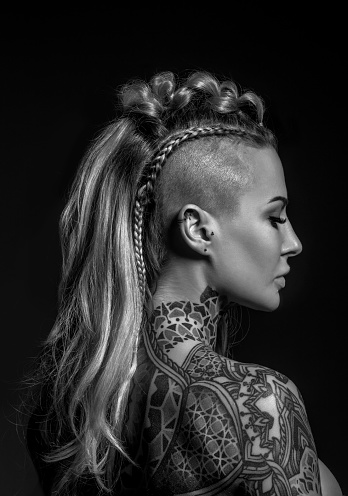 Side portrait of a tattooed viking blonde female and her unique hairstyle