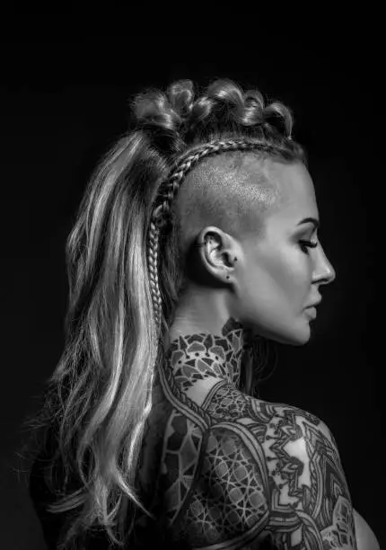 Photo of Side portrait of a tattooed viking blonde female and her unique hairstyle