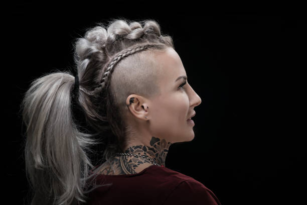 Side portrait of a tattooed viking blonde female and her unique hairstyle Side portrait of a tattooed viking blonde female and her unique hairstyle half shaved hairstyle stock pictures, royalty-free photos & images