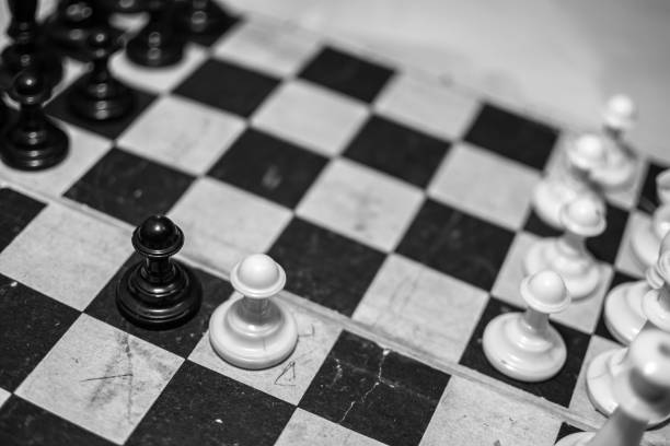 istock Old chess on an old chessboard. Black and white photo. Confrontation game. 1296400453