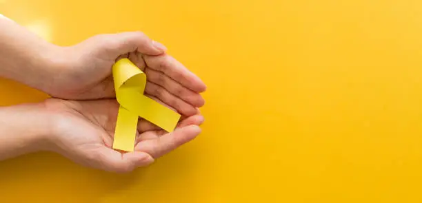 Photo of Woman hands with yellow gold ribbons on yellow background