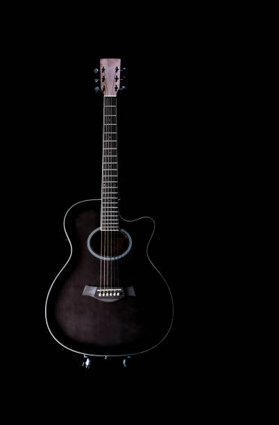 istock black acoustic guitar with a white profile around it on a black background, placed on a stand in a vertical position, copy space 1296406262