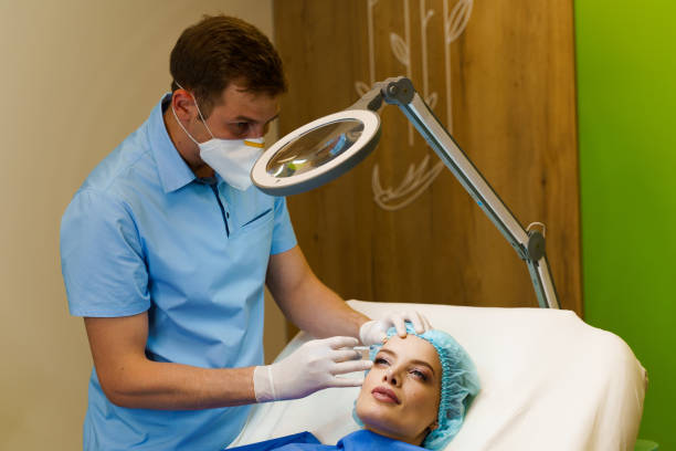 istock Lips augmentation injections for attractive girl. Plastic surgeon does injection in lip in medical clinic. Cosmetic rejuvenating facial treatment. Empty space for advert 1296407367