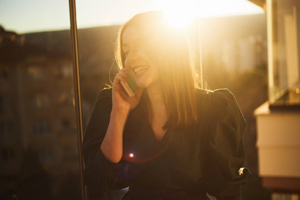 istock A women is talking on the phone sunset on the balcony 1296408611