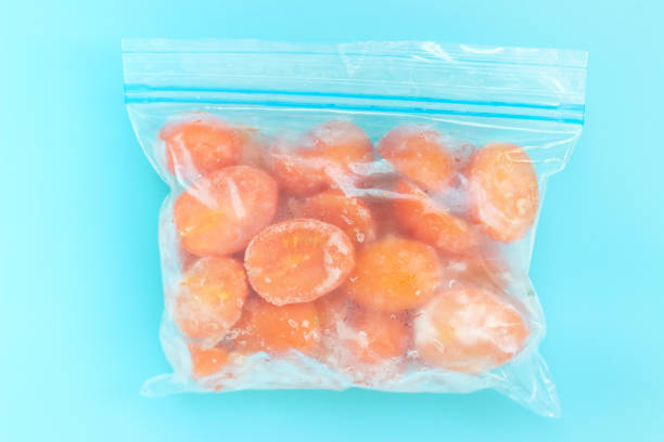 istock Package with frozen tomatoes on blue background, concept of saving leftovers. 1296410859