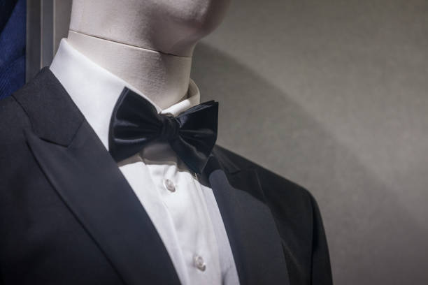 Selective blur of a dummy wearing a black tuxedo, a white shirt and a black bowtie. it is a typical male suit and costume for formal events. Picture of a dumy wearing a tuxedo and a black bow tie. Black tie is a semi-formal Western dress code for evening events, originating in British and American conventions for attire in the 19th century. In British English, the dress code is often referred to synecdochically by its principal element for men, the dinner suit or dinner jacket. dinner jacket stock pictures, royalty-free photos & images