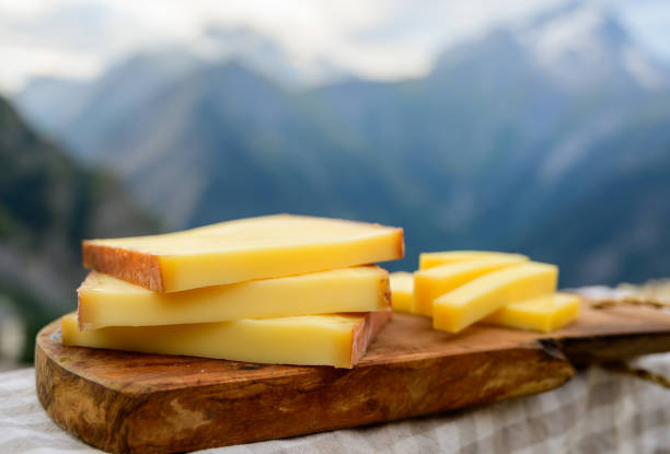 Cheese collection, French comte, beaufort or abondance cow milk cheese served outdoor with Alps mountains peaks on background Cheese collection, French comte, beaufort or abondance cow milk cheese served outdoor with Alps mountains peaks in summer on background jura france photos stock pictures, royalty-free photos & images