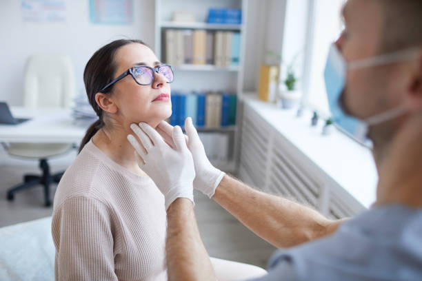 Doctor Examining Woman in Clinic Close up of unrecognizable male doctor palpating throat of woman while examining female patient during consultation in clinic throat stock pictures, royalty-free photos & images