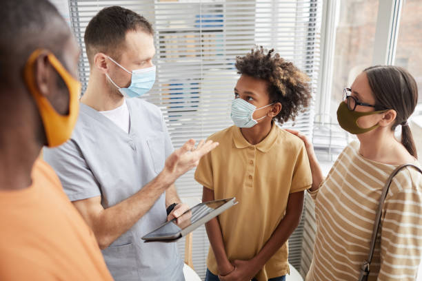 medico che parla con la famiglia in clinica - doctor patient doctors office teenager foto e immagini stock