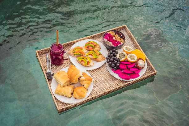 istock Breakfast tray in swimming pool, floating breakfast in luxury hotel smoothies and fruit plate, smoothie bowl by the hotel pool. Exotic summer diet. Tropical beach lifestyle. Bali Trend 1296418588