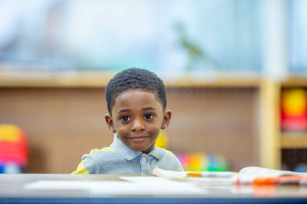 A super adorable boy of African ethnicity in his preschool classroom.
