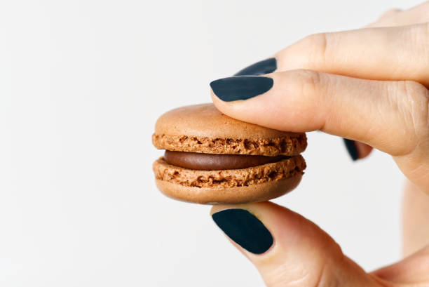 istock Macaron in woman hand on white background with copy space 1296429757