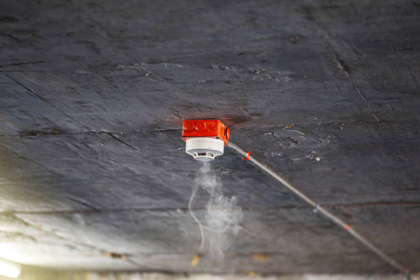 Smoke detector on white ceiling Smoke detector on precast concrete ceiling. Close up of smoke detector for fire protection systems. Selective focus. fire inspection stock pictures, royalty-free photos & images