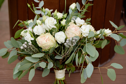 Close up of lush wedding bouquet of white flowers and greenery on wood background, copy space. Bridal bouquet