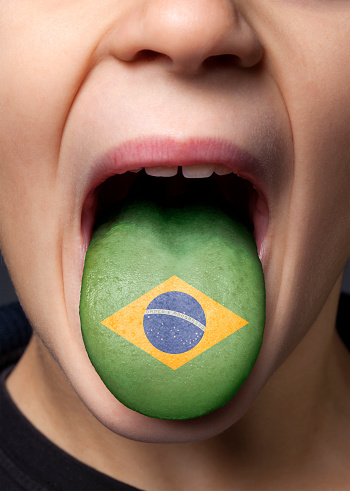 Little boy sticking out his tongue with painted Brazilian flag.
