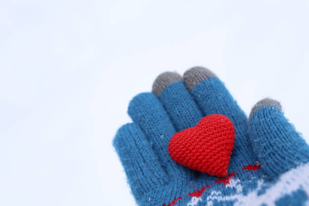coração vermelho na palma da mão em luva de malha quente contra a neve - glove winter wool touching - fotografias e filmes do acervo