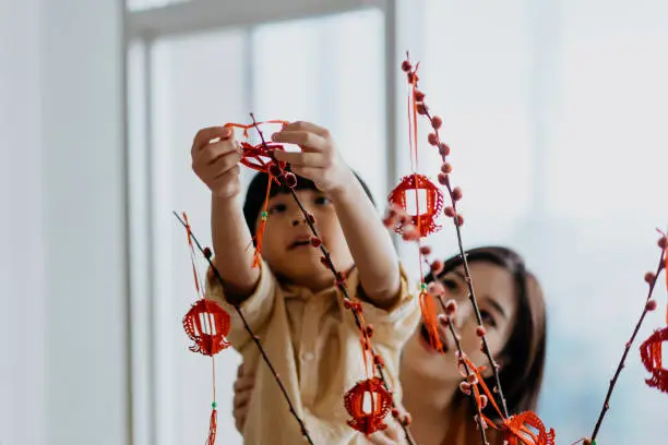 Photo of Asian young chinese boy helping mother to hang Chinese New Year decoration