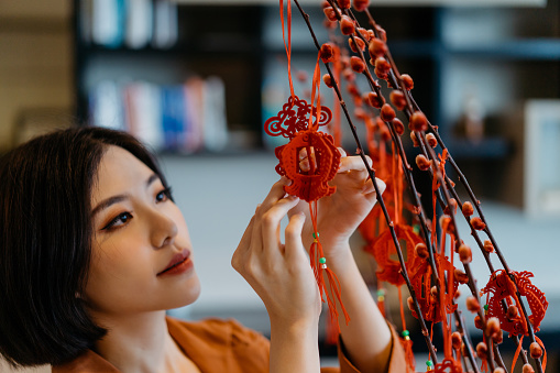 Image of an Asian Chinese woman hanging decoration on a plant and prepare for Chinese New Year