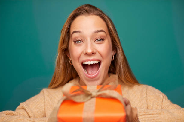 Surprised young woman holding Christmas gift.