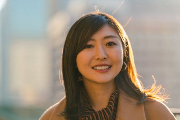 Back lit portrait of beautiful woman during sunset in city A back lit portrait of a beautiful woman smiing for the camra during sunset in city. only japanese stock pictures, royalty-free photos & images