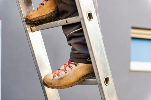 Close up view of roofer climbing on aluminum ladder