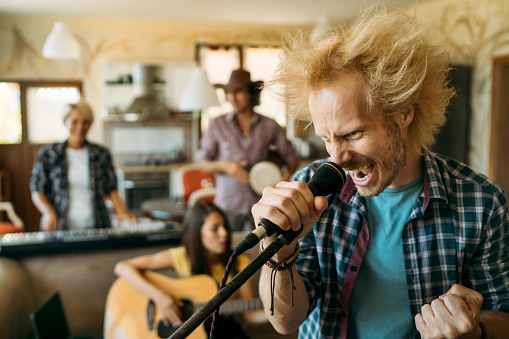 Angry rocker singer screaming at the microphone while the musicians playing on the background