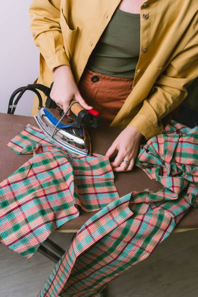 istock Female ironing plaid fabric in sewing workshop 1296451379